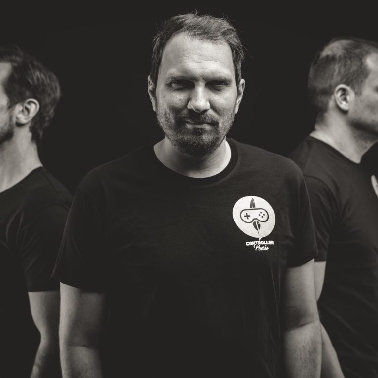 Controller Poesie – Studio-Portrait Yetivin Foto von Creator YetiVin in schwarzem T-Shirt mit Controller-Poesie-Logo, frontal fotografiert vor dunklem Hintergrund.